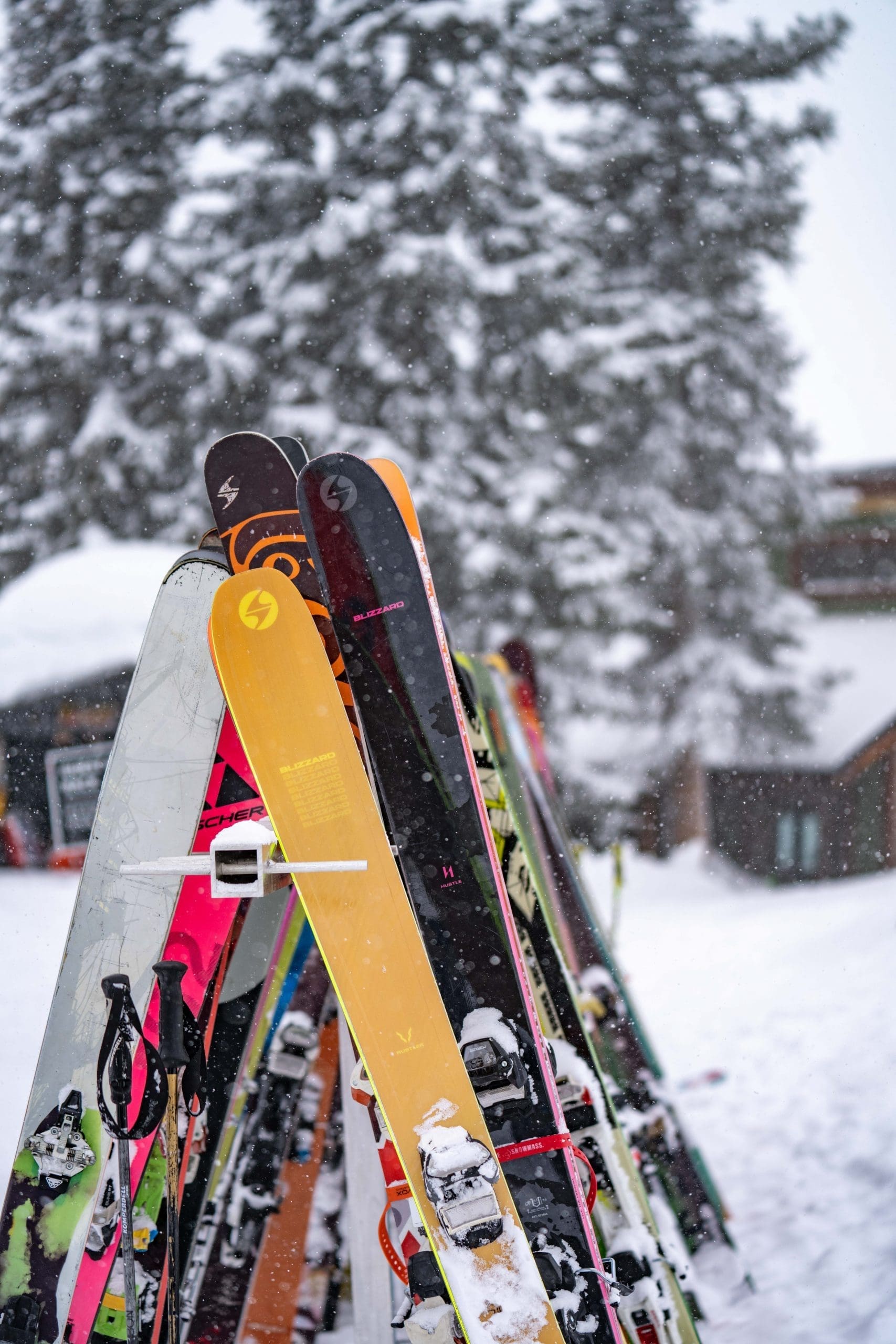 lineup of blizzard skis on outdoor ski rack in snow