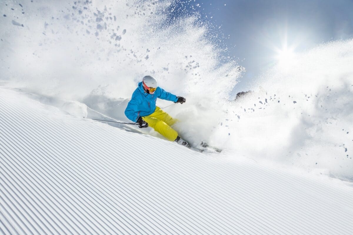 Skier skiing downhill during sunny day in high mountains exercises to prepare for skiing